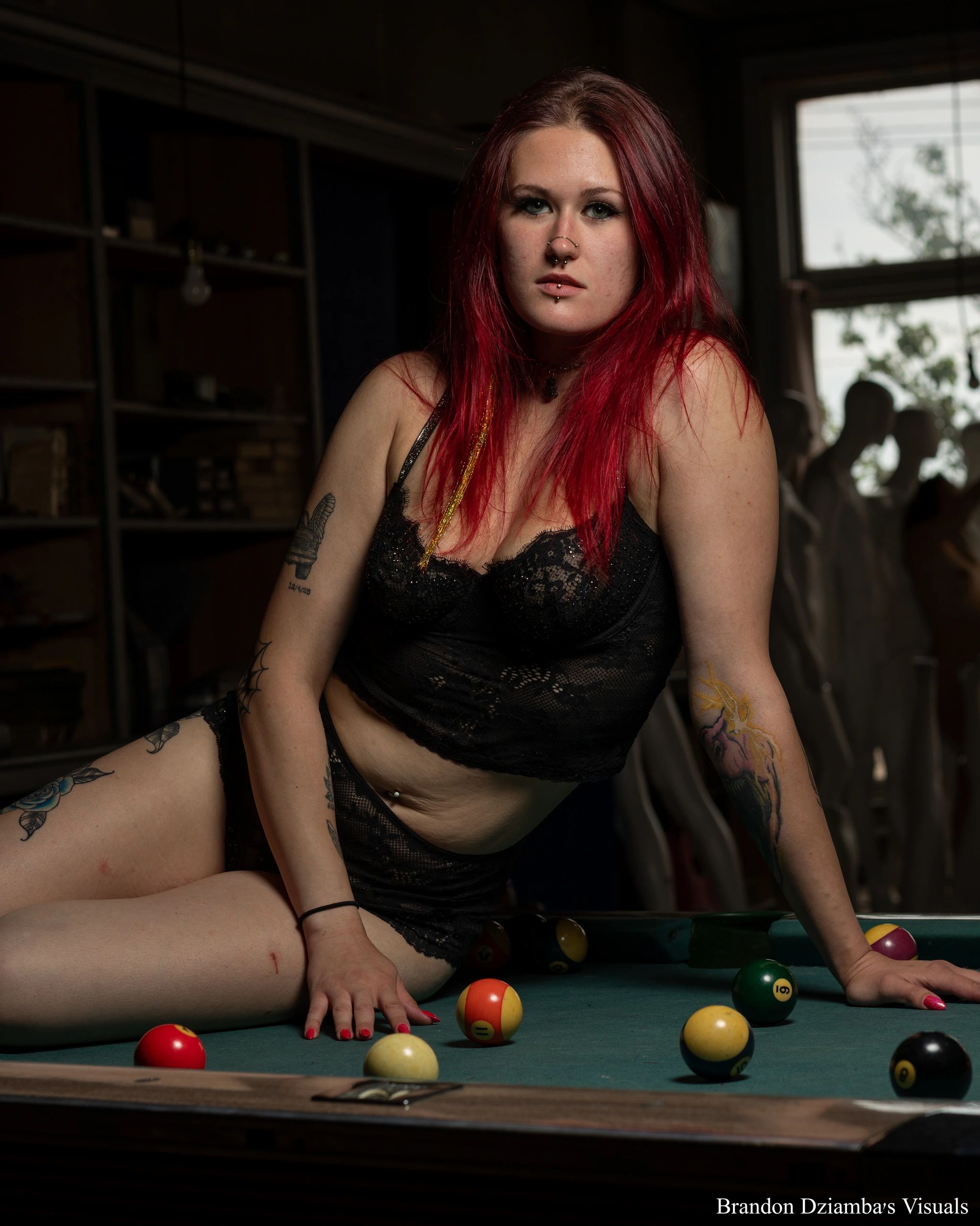 Woman with red hair in black lingerie on a pool table.