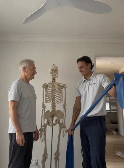 Two men exercise with a skeleton model in a room.
