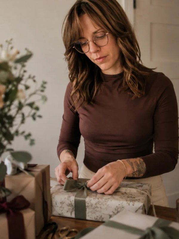 Woman wrapping a gift with a bow.