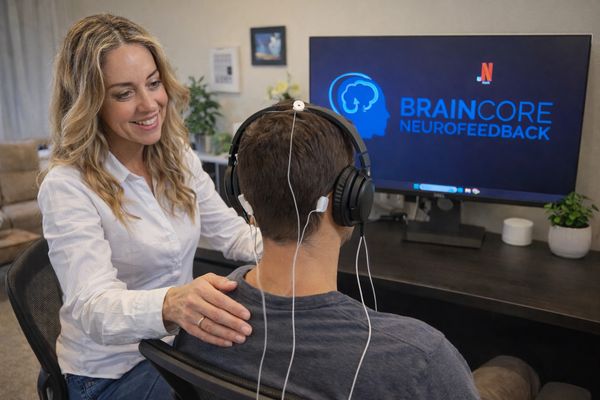 Woman guiding a man during a neurofeedback session using BrainCore technology.