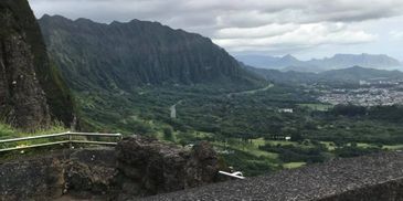 Scenic mountain valley under a cloudy sky with lush greenery.
