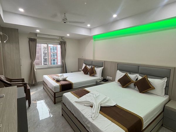 Modern hotel master suite with two double beds and green accent lighting.