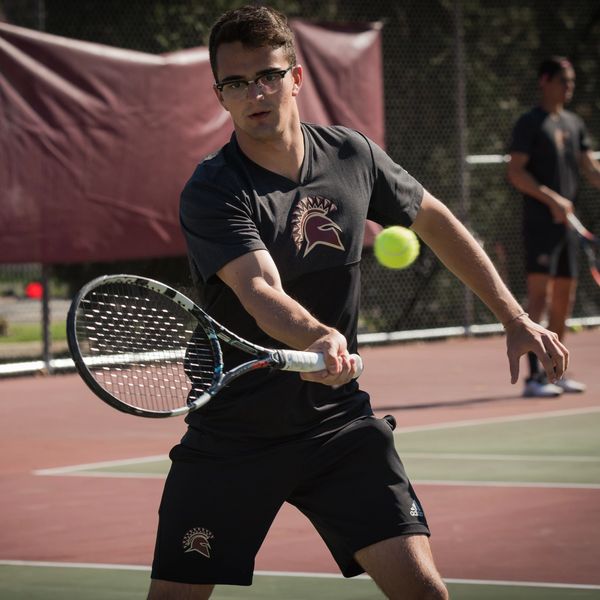 Action shot of Coach Andreu hitting a forehand volley while playing a college match