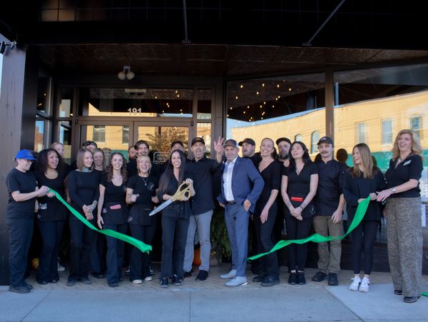 Group of people at a ribbon-cutting event outside a building.