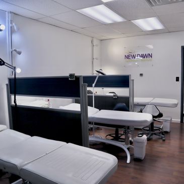 Modern clinic room with multiple treatment beds and partitions.