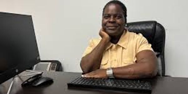 Smiling woman sitting at desk with computer keyboard.