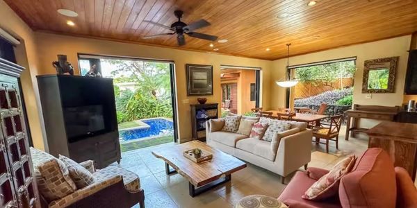 Cozy living room with natural wood ceiling and pool view.