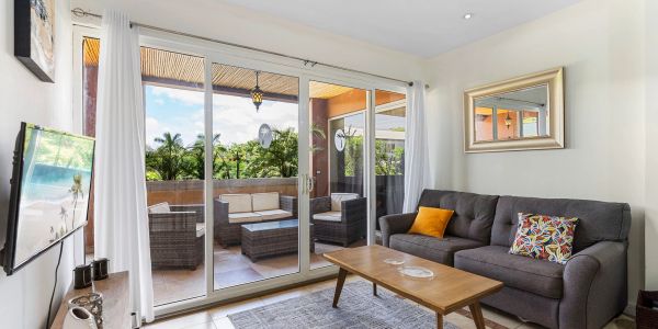 Cozy living room with a gray sofa and glass doors opening to a patio with wicker furniture.