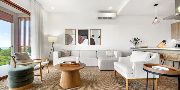 Bright modern living room with white furniture and natural wood accents.