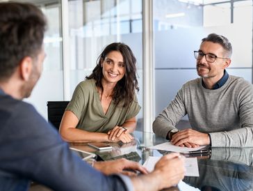 A couple smiling during a meeting with a professional in a modern office.