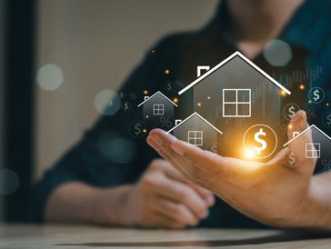 Hand presenting digital houses and dollar symbols symbolizing real estate investment.