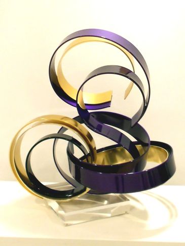 Abstract sculpture with intertwined purple and gold metallic ribbons.