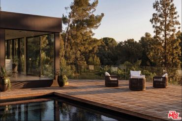 Modern outdoor deck with pool and chairs.
