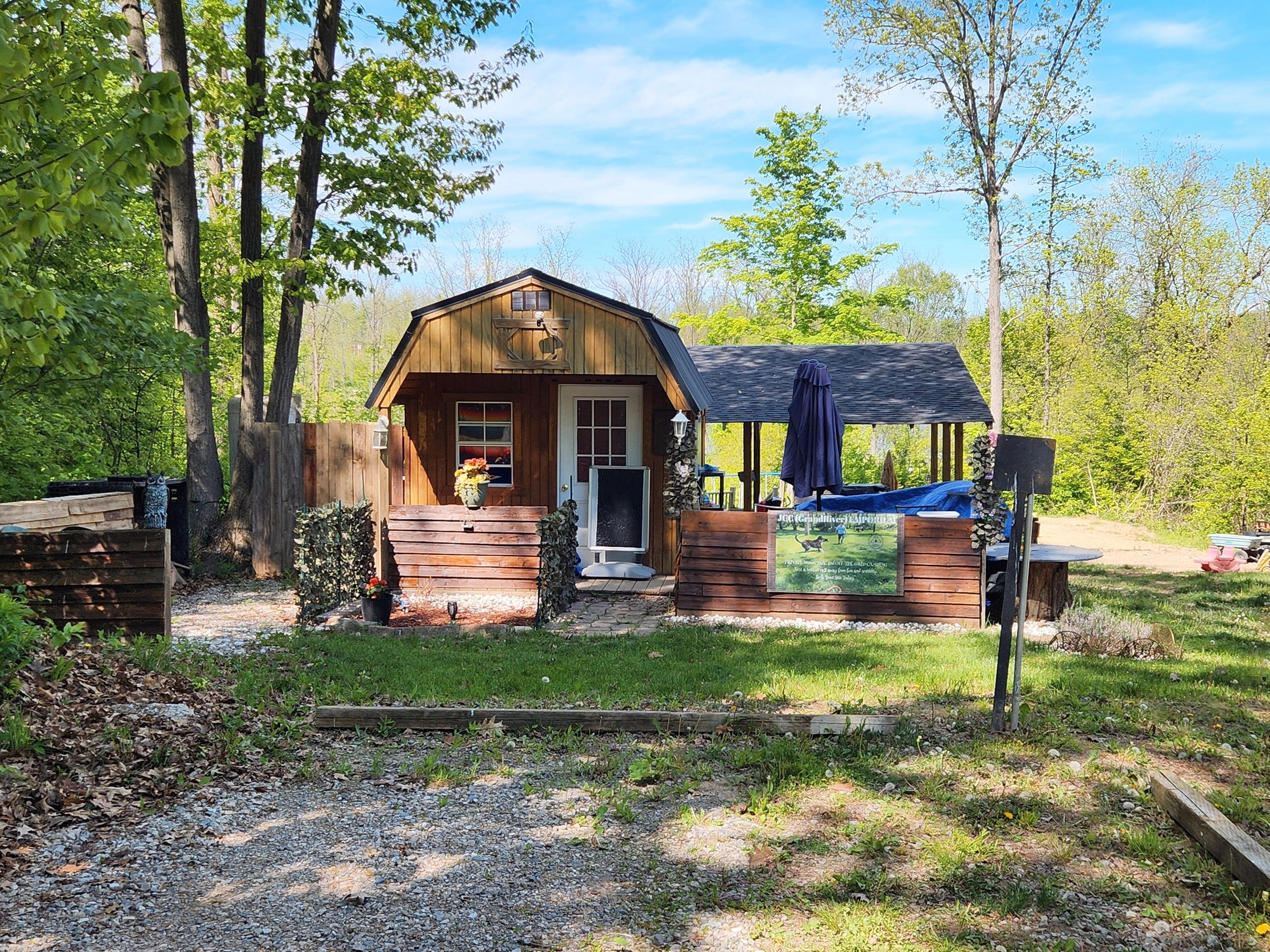 Rustic wooden cabin with a small porch surrounded by greenery and trees.