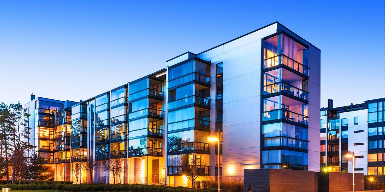 Modern apartment buildings lit at dusk.