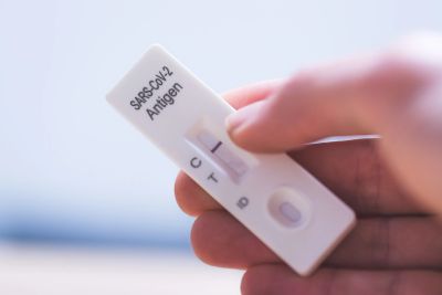Hand holding a negative SARS-CoV-2 antigen test device.