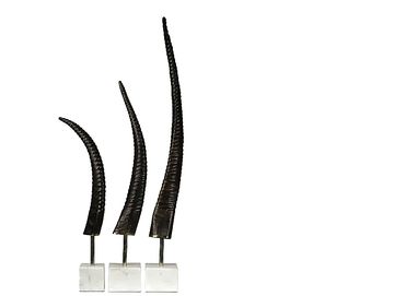 Three curved black sculptures on clear bases.