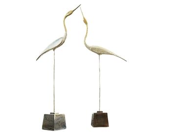 Two bird sculptures on stands facing each other.