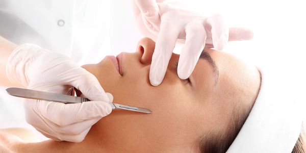 A person receiving a facial treatment with a scalpel from a professional.