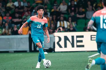 Soccer player in teal uniform controlling the ball on the field during a match.