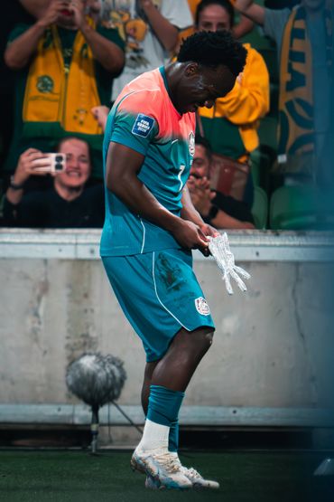 Soccer player adjusts gloves on the field during a match.