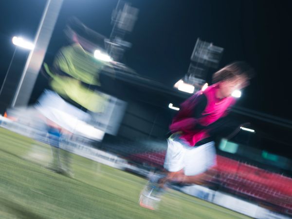 Blurred action shot of two soccer players in motion during a night game.