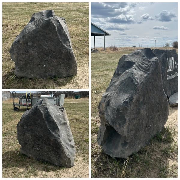 Large, gray, triangular stone on grass.