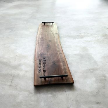 Wooden serving tray with handles on a concrete floor.