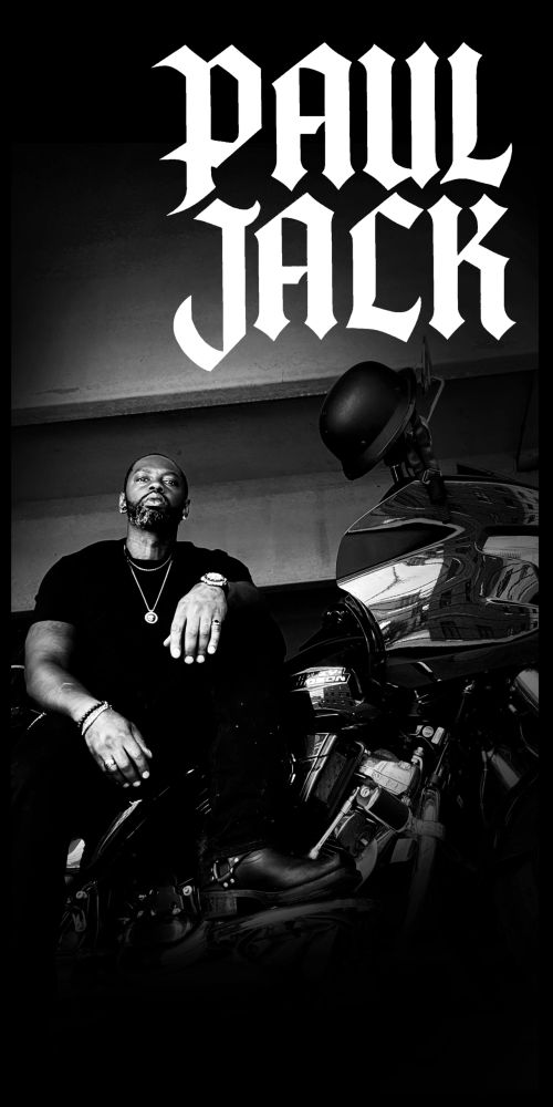Man posing on a motorcycle with bold text "PAUL JACK" above.