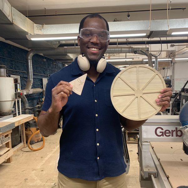 Dr. Ayotunde Ayobello holding a wellness pizza prototype