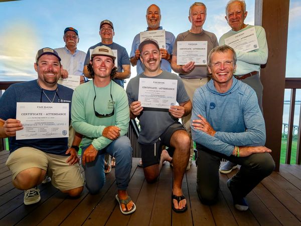 Group of men proudly displaying their saltwater fly fishing certificates on a porch.