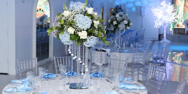 Elegant event tables with blue and white floral centerpieces and blue napkins.