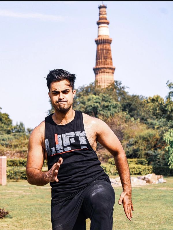 A man in black athletic wear running outdoors with a historical tower in the background.