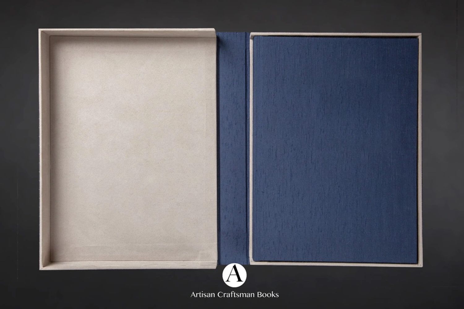 An open, empty book box with a blue fabric lining and a beige outer frame.