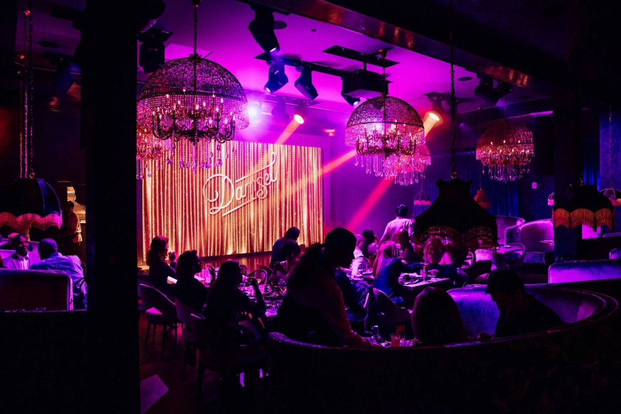 A lively nightclub with purple lighting and elegant chandeliers.