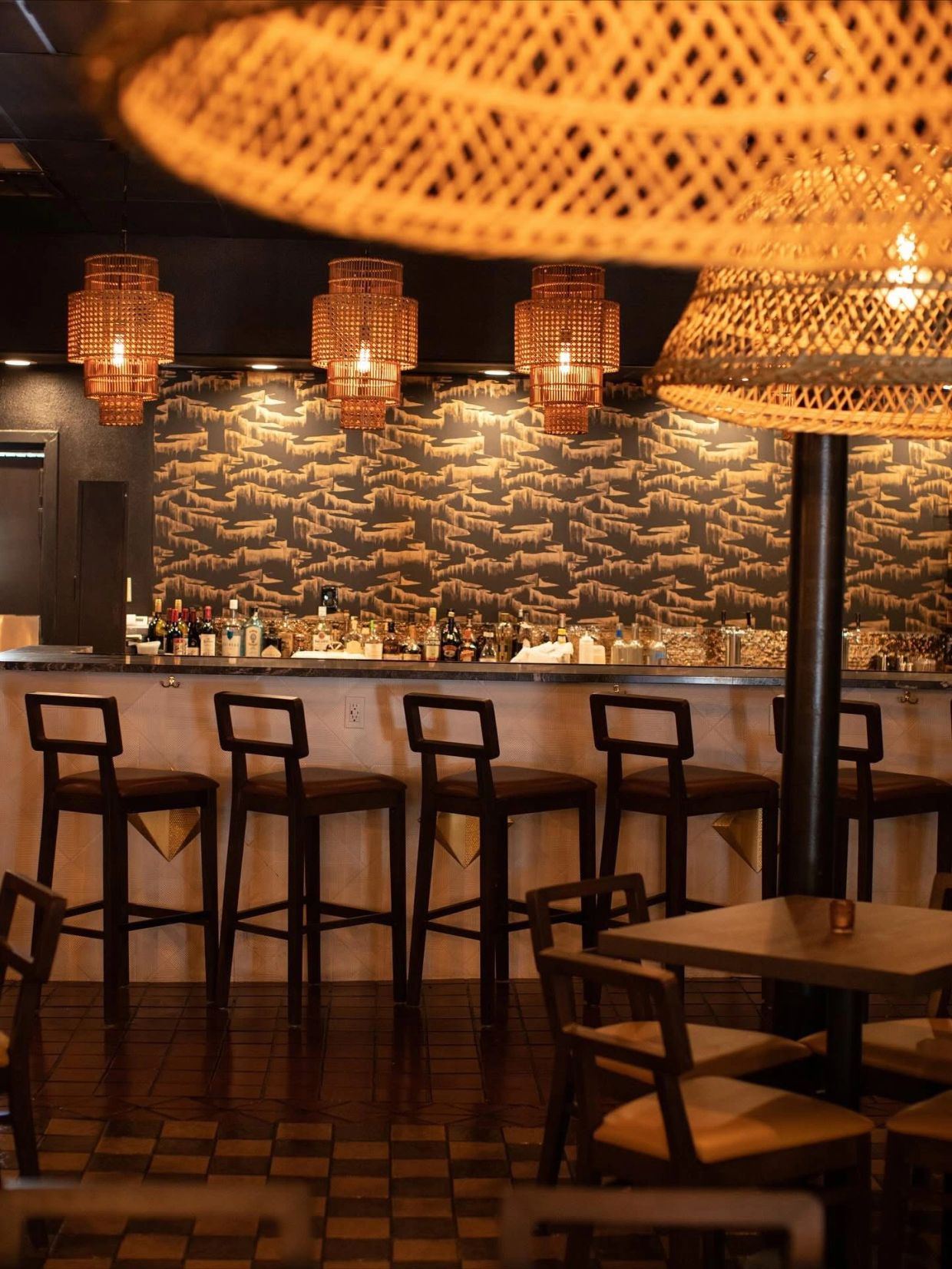 Cozy bar with wooden stools and warm lighting from woven lampshades.