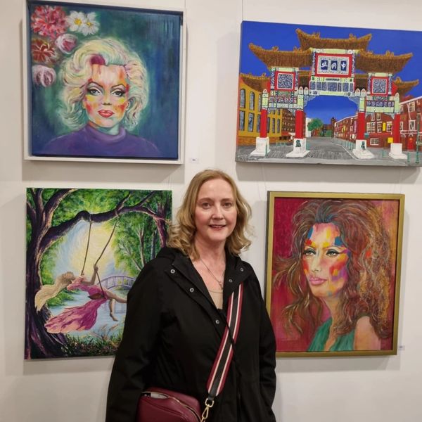 The artist, Sharon Melsome standing in front of two of her icon portrait paintings at the Atkinson
