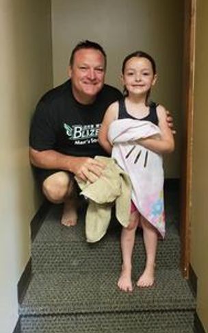 A man and a young girl posing together for a photo in a doorway