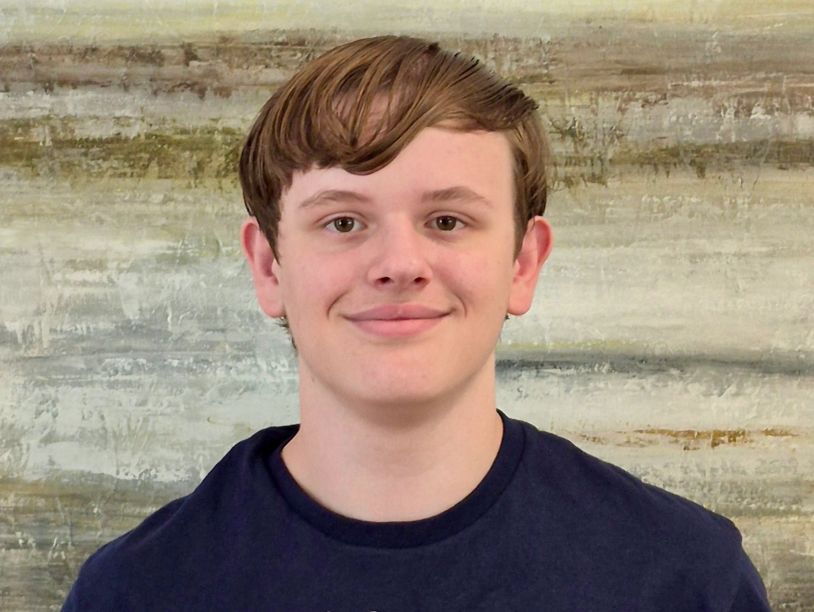 Young man smiling with a textured wall background.
