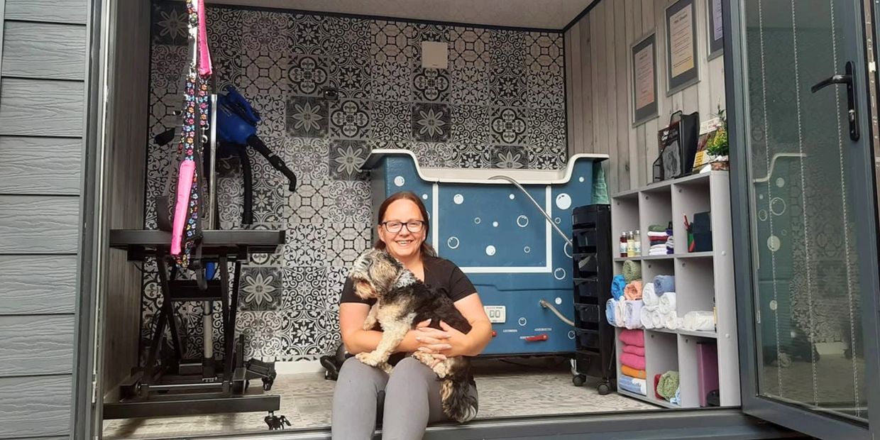 Woman sitting with a dog in a pet grooming room.