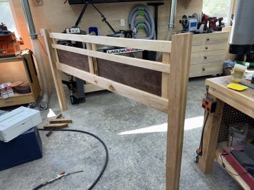 A partially assembled wooden bed frame in a workshop.