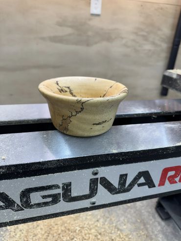 Handcrafted wooden bowl with natural grain patterns on a workbench.