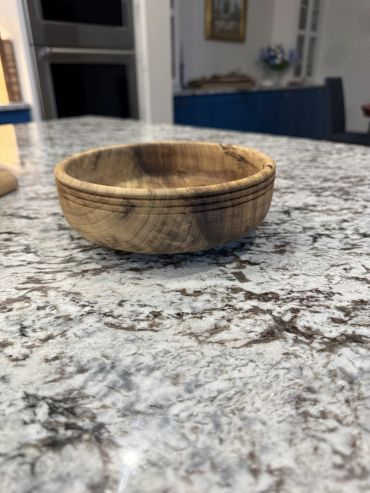 A small wooden bowl on a granite countertop in a kitchen.