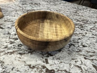 Handcrafted wooden bowl on a granite countertop.