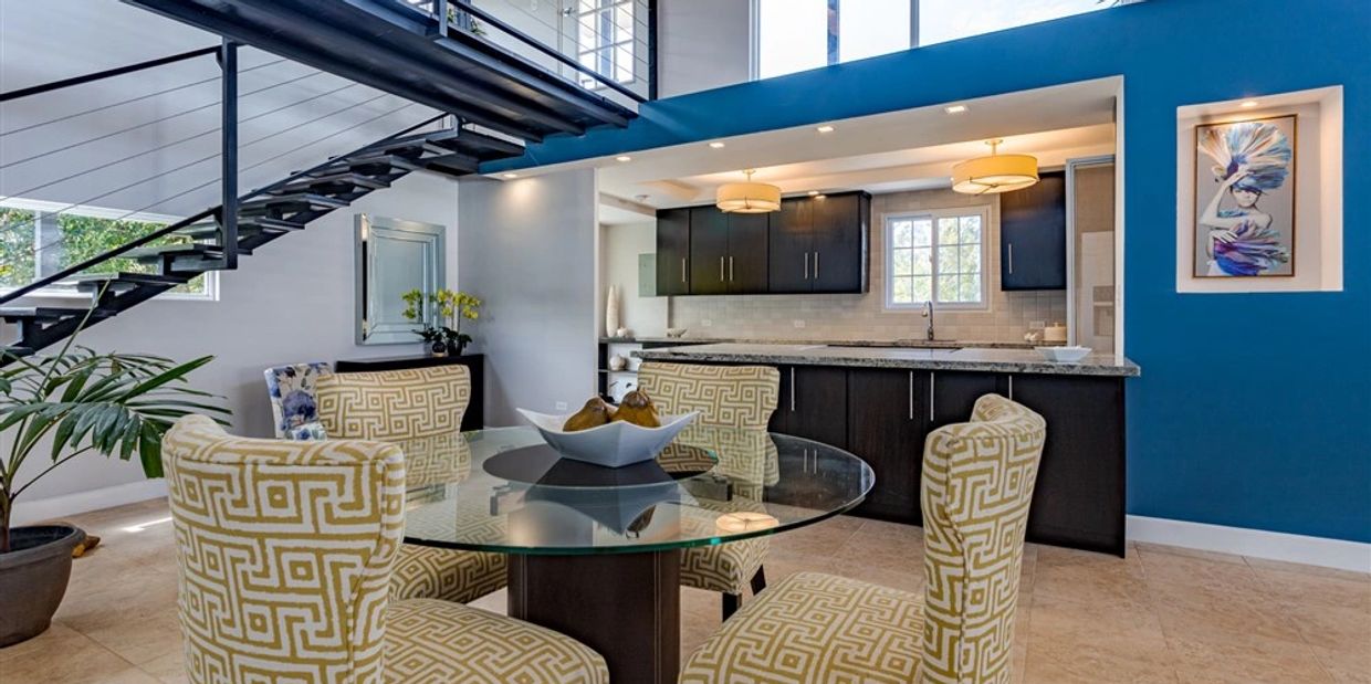 View of dining area, open kitchen and floating staircase in Alto Boquete home.