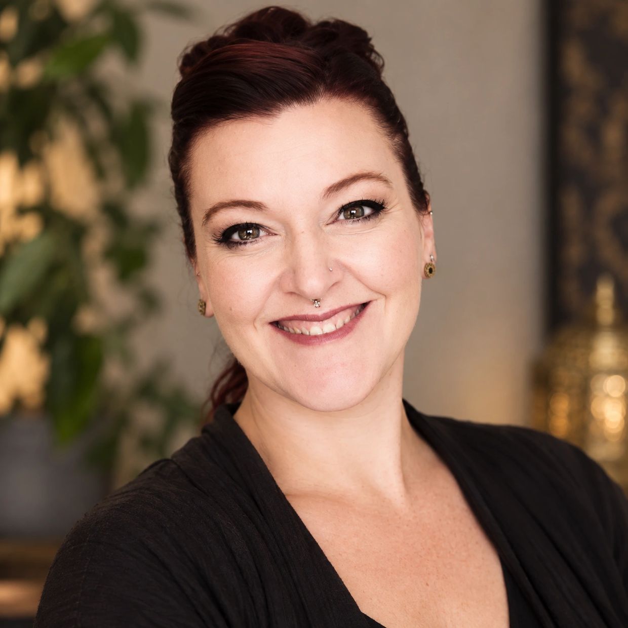 Smiling woman with red hair and septum piercing.