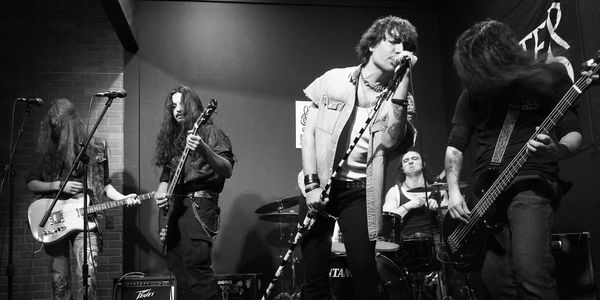 Black and white photo of a rock band performing on stage.