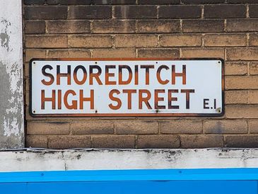 Street sign for Shoreditch High Street on a brick wall.