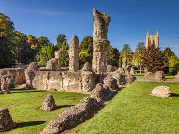 Ancient stone ruins with a church tower in the background under a clear blue sky.