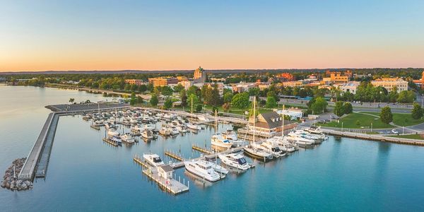 A marina with boats docked by a waterfront town at sunset.